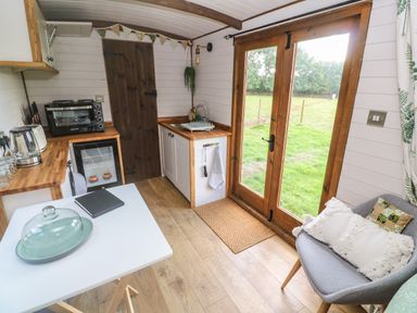A small kitchen area with wooden countertops a sink a toaster and an oven next to double glass doors with a view of a grassy yard at Fern in Broad Langdon near Wainhouse Corner