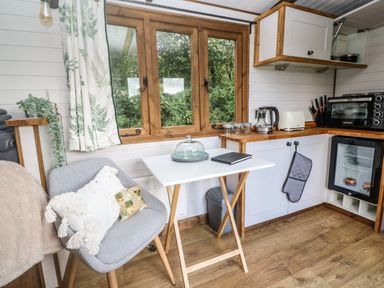 A small kitchen area with a gray chair and white table near a window at Fern in Broad Langdon near Wainhouse Corner