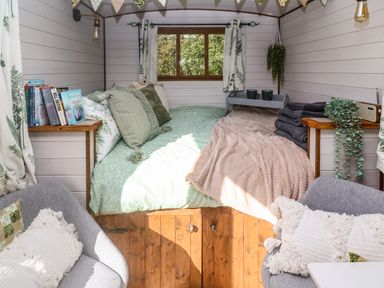 A small bedroom with a green bedspread pillows books and towels at Fern in Broad Langdon near Wainhouse Corner