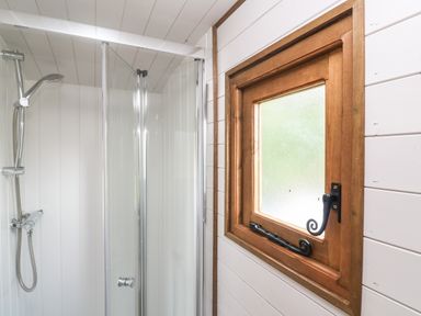 A shower area with a glass door and a wooden framed window in a bathroom at Fern Broad Langdon near Wainhouse Corner