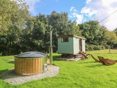 A wooden hot tub and a small cabin on wheels with stairs on a grassy area with trees at Fern Broad Langdon near Wainhouse Corner