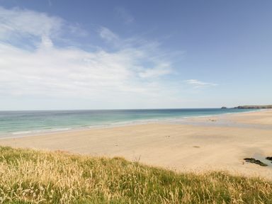A beach with sand grass and ocean under a blue sky at Fern Broad Langdon near Wainhouse Corner