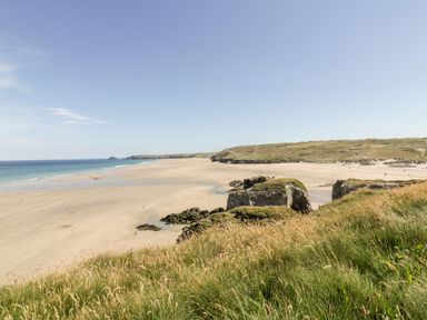 A beach with sandy shore grass in foreground and hills in the distance at Fern in Broad Langdon near Wainhouse Corner