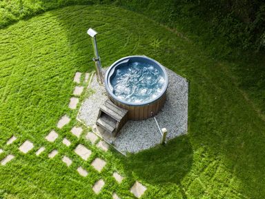 An outdoor hot tub with wooden steps on a gravel area surrounded by grass at Fern Broad Langdon near Wainhouse Corner