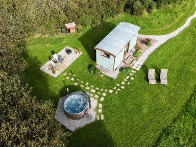 A small cabin with path leading to a hot tub two lounge chairs and a seating area outdoors at Fern Broad Langdon near Wainhouse Corner