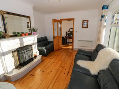 A living room with black leather sofas a white fireplace wooden floor and plants on the mantel at Castle Demesne House in Clifden County Galway