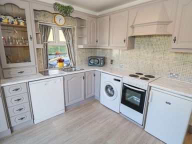 A kitchen with cabinets dishwasher washing machine oven fridge microwave and a small window at Castle Demesne House Clifden County Galway