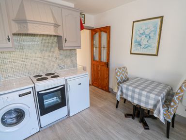 A kitchen with a washing machine stove fridge a small dining table with two chairs and a framed picture on the wall at Castle Demesne House in Clifden County Galway