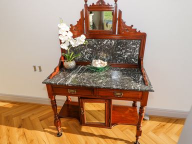 A wooden vanity with a marble top and mirror with a white orchid and a bowl of shells on it at Castle Demesne House in Clifden County Galway