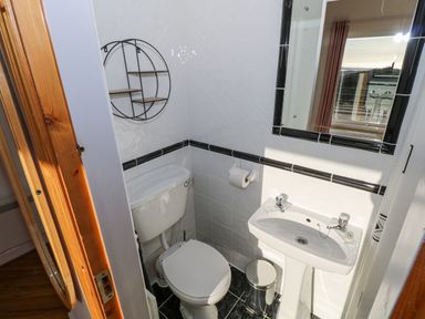 A small bathroom with a toilet sink mirror and circular wall shelf at Castle Demesne House in Clifden County Galway