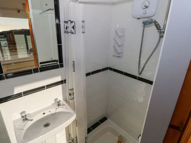 A bathroom with a white sink a mirror shower with a shower curtain and a water heater at Castle Demesne House Clifden County Galway
