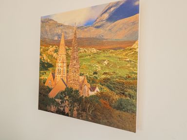 A wall with a mounted photograph of a church with two spires surrounded by trees and hills at Castle Demesne House in Clifden County Galway