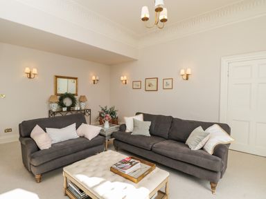 A living room with two grey sofas and a white ottoman coffee table at Rockstowes House in Uley near Dursley
