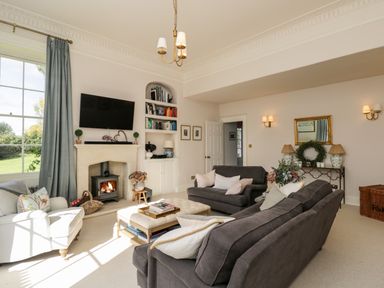 A living room with sofas and a fireplace with TV above at Rockstowes House Uley near Dursley