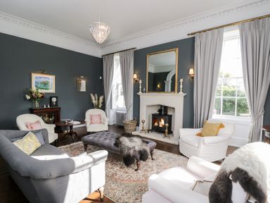 A living room with a fireplace ottoman sofas and armchairs at Rockstowes House in Uley near Dursley