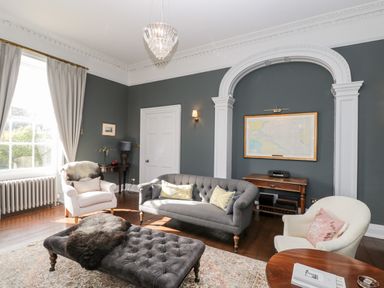 A sitting room with armchairs a sofa an ottoman and framed map on the wall at Rockstowes House in Uley near Dursley