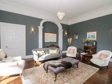 A sitting room with white and gray sofas a patterned rug and framed pictures on the walls at Rockstowes House Uley near Dursley