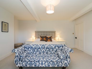 A bedroom with a bed and patterned sofa at Rockstowes House in Uley near Dursley