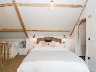 A bedroom with a bed and pillows under exposed wooden beams at Rockstowes House in Uley near Dursley