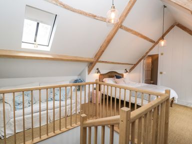 A bedroom with a bed sofa wooden railing skylight at Rockstowes House in Uley near Dursley
