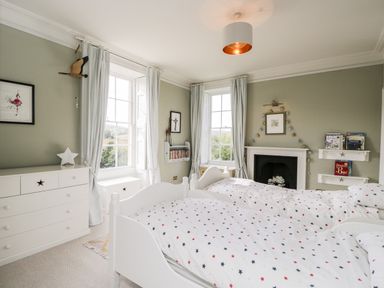 A bedroom with two single beds a chest of drawers windows and a fireplace at Rockstowes House in Uley near Dursley
