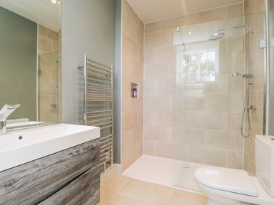 A bathroom with a shower area glass divider toilet sink and towel rack at Rockstowes House Uley near Dursley