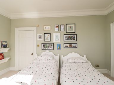 A bedroom with two single beds with star-patterned bedding and framed pictures on the wall at Rockstowes House in Uley near Dursley