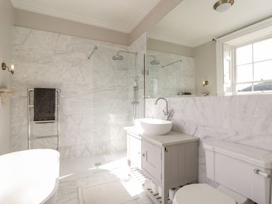 A bathroom with a shower area towel rack sink with cabinet toilet and window at Rockstowes House Uley near Dursley