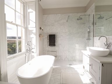 A bathroom with a large window bathtub shower and sink at Rockstowes House in Uley near Dursley