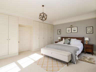 A bedroom with a bed two bedside tables lamps built in wardrobes and pendant light at Rockstowes House Uley near Dursley