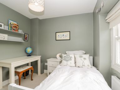 A bedroom with a single bed white desk wooden stool globe and window at Rockstowes House Uley near Dursley
