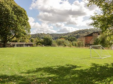A grassy field with two small soccer goals and trees surrounding the area at Rockstowes House in Uley near Dursley