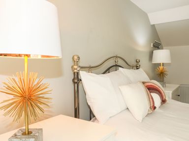 A bedroom with a metal bed frame white bedding and two bedside tables with lamps at Bodwena in Moelfre