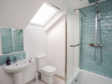 A bathroom with a sink toilet and bathtub with shower at Bodwena in Moelfre