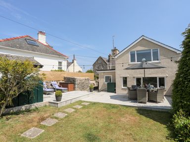 A backyard with patio furniture and umbrella near a house at Bodwena in Moelfre