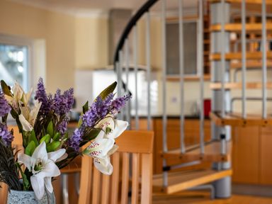 A dining area with a vase of flowers on a table and a spiral staircase in the background at Blue Ridge in Polzeath