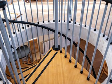 A spiral staircase with wooden steps and vertical metal railings in a room with wooden floor at Blue Ridge in Polzeath