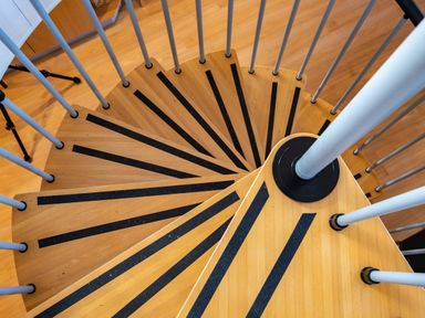 A wooden spiral staircase with black anti-slip strips and metal railings at Blue Ridge in Polzeath