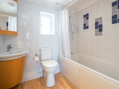 A bathroom with a sink cabinet toilet bathtub shower and a window at Blue Ridge in Polzeath
