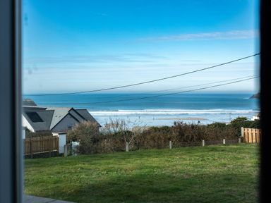 A view of the ocean with waves and houses in the foreground at Blue Ridge in Polzeath
