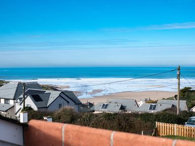Ocean view with beach waves houses and power lines at Blue Ridge in Polzeath