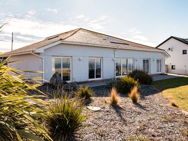 A single-story house with sliding glass doors and landscaped garden at Blue Ridge in Polzeath