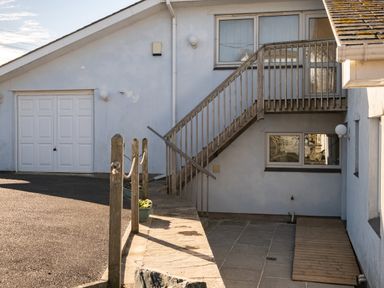 Exterior view of a building with staircase leading to upper door and garage doors at Blue Ridge in Polzeath