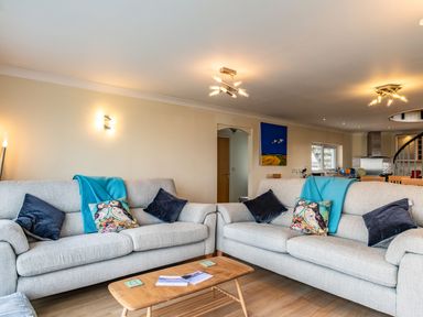 A living room with two gray sofas with cushions and blankets and a wooden coffee table at Blue Ridge in Polzeath