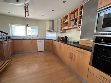 A kitchen with wooden cabinets black countertops dishwasher stainless steel oven and microwave at Blue Ridge in Polzeath