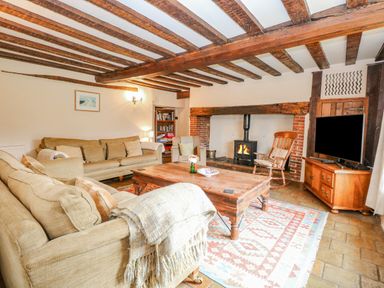 A living room with sofas a wooden coffee table a fireplace and a television at Manor Farm House in Bacton