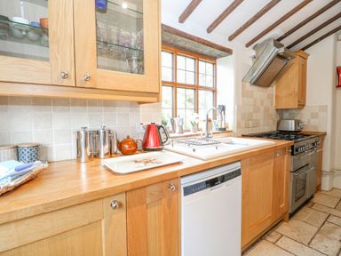 A kitchen with wooden cabinets a sink dishwasher and stove at Manor Farm House in Bacton