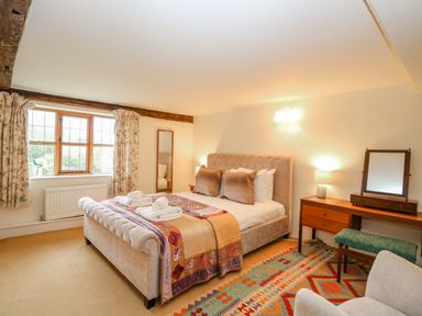 A bedroom with a bed a wooden dressing table with a mirror a rug and a window at Manor Farm House in Bacton