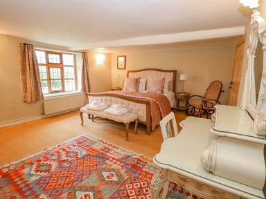 A bedroom with a bed a patterned rug a dressing table and a rocking chair at Manor Farm House in Bacton