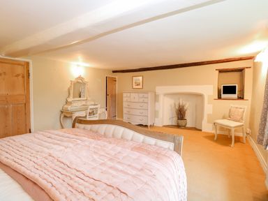 A bedroom with a bed a vanity table a chest of drawers a chair and a small television at Manor Farm House in Bacton